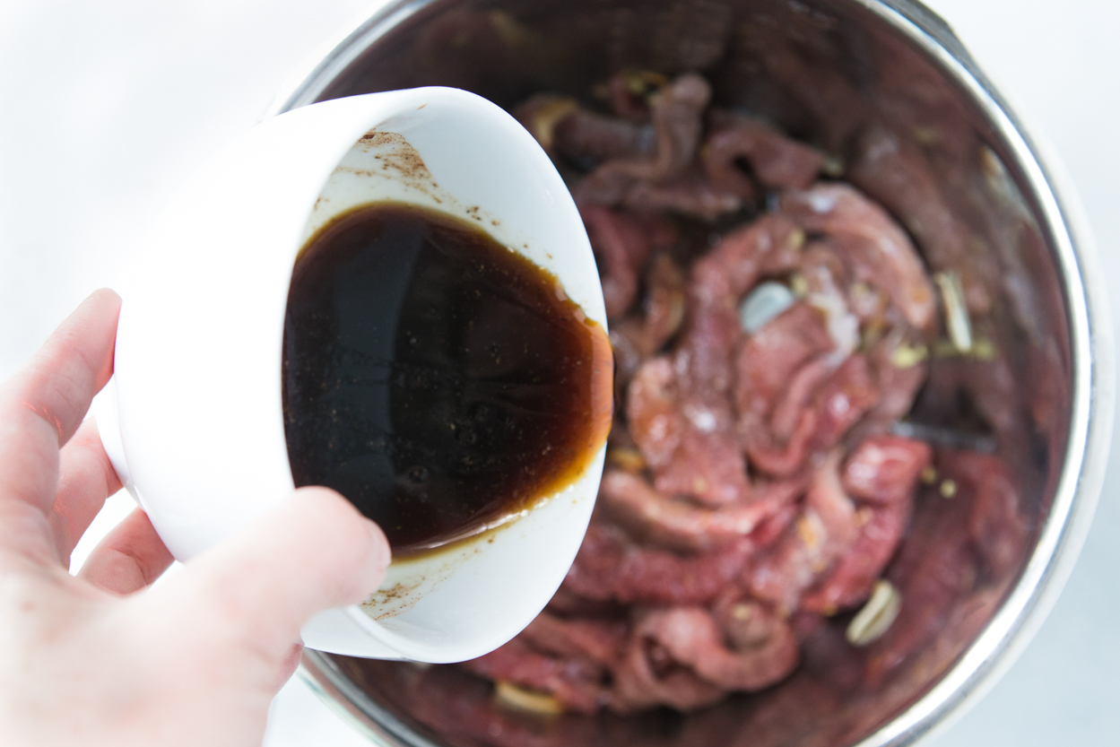 Pouring beef and broccoli sauce into the Instant Pot