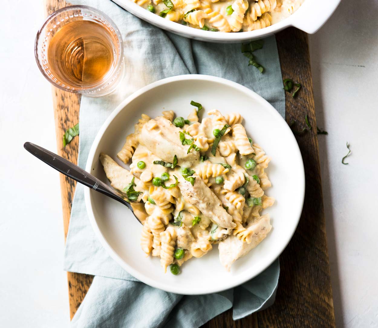 Instant Pot Chicken Alfredo in a white dish with a dairy free alfredo sauce peas and basil