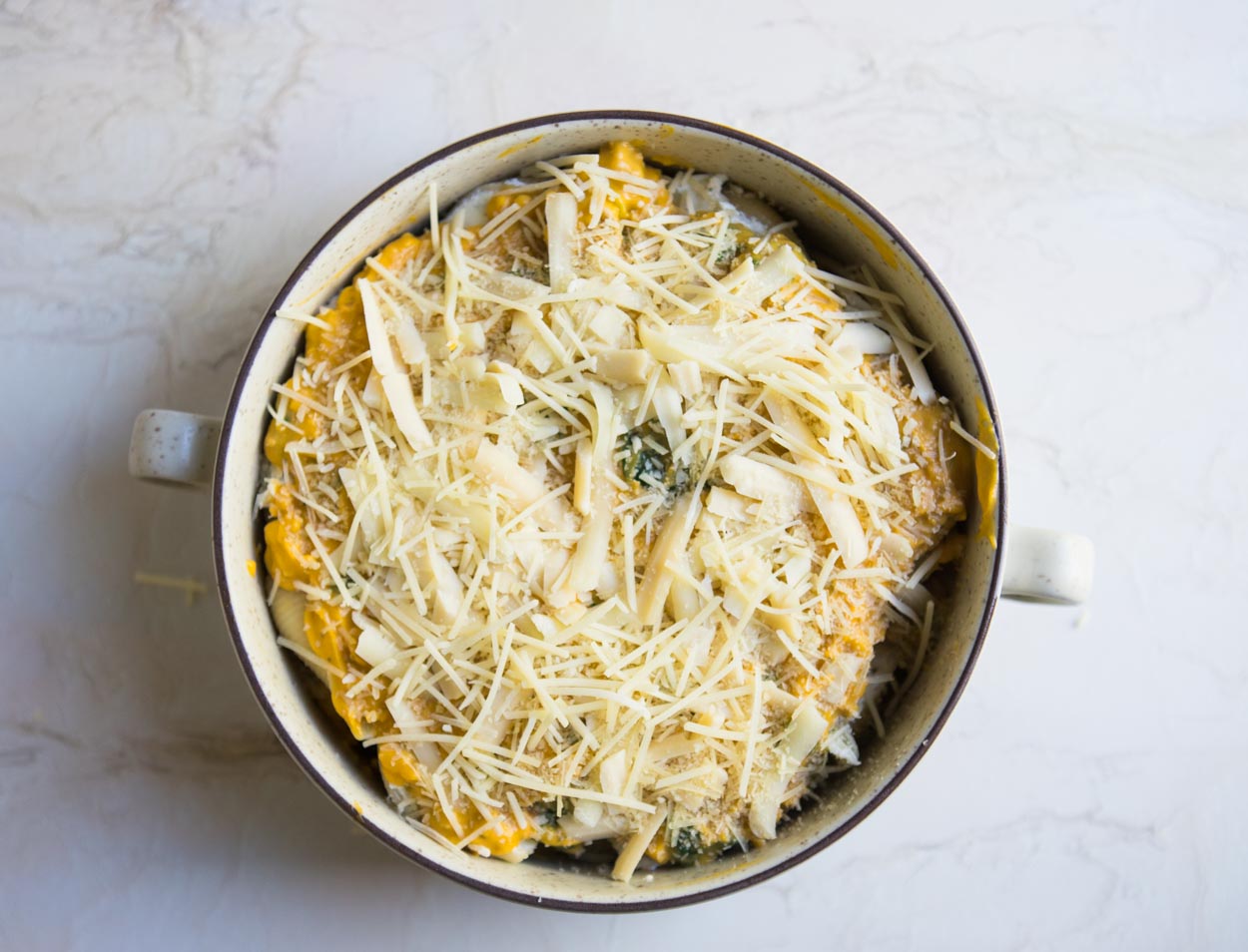 Stuffed pasta shells in a cream colored bowl on a white background