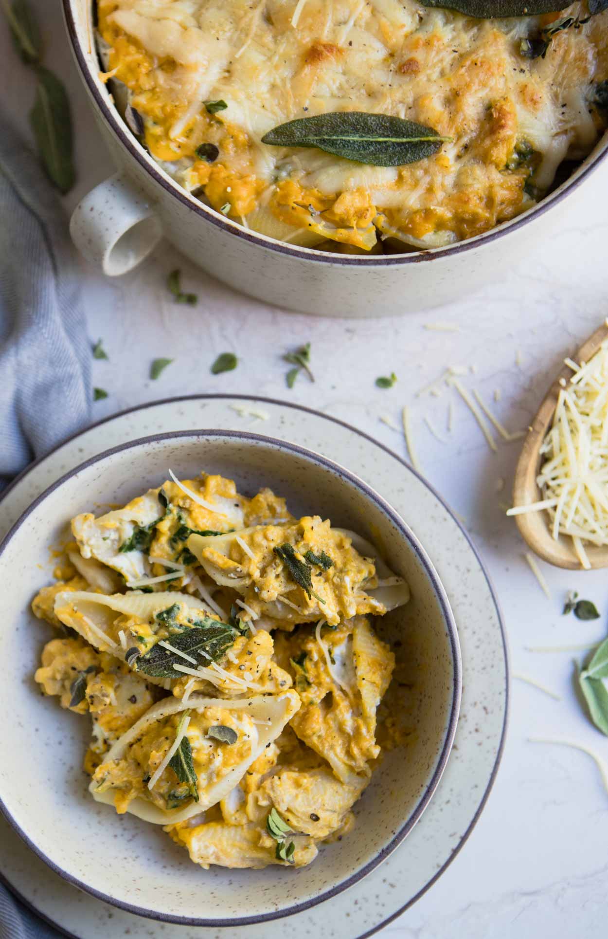 Stuffed pasta shells in a cream colored bowl on a white background