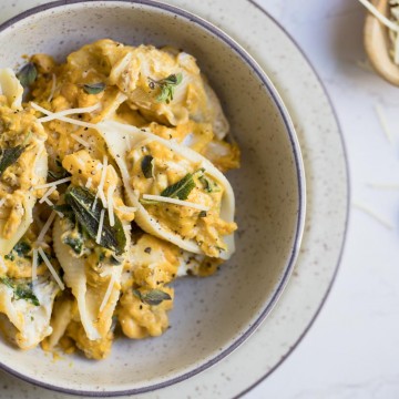 Stuffed pasta shells in a cream colored bowl on a white background