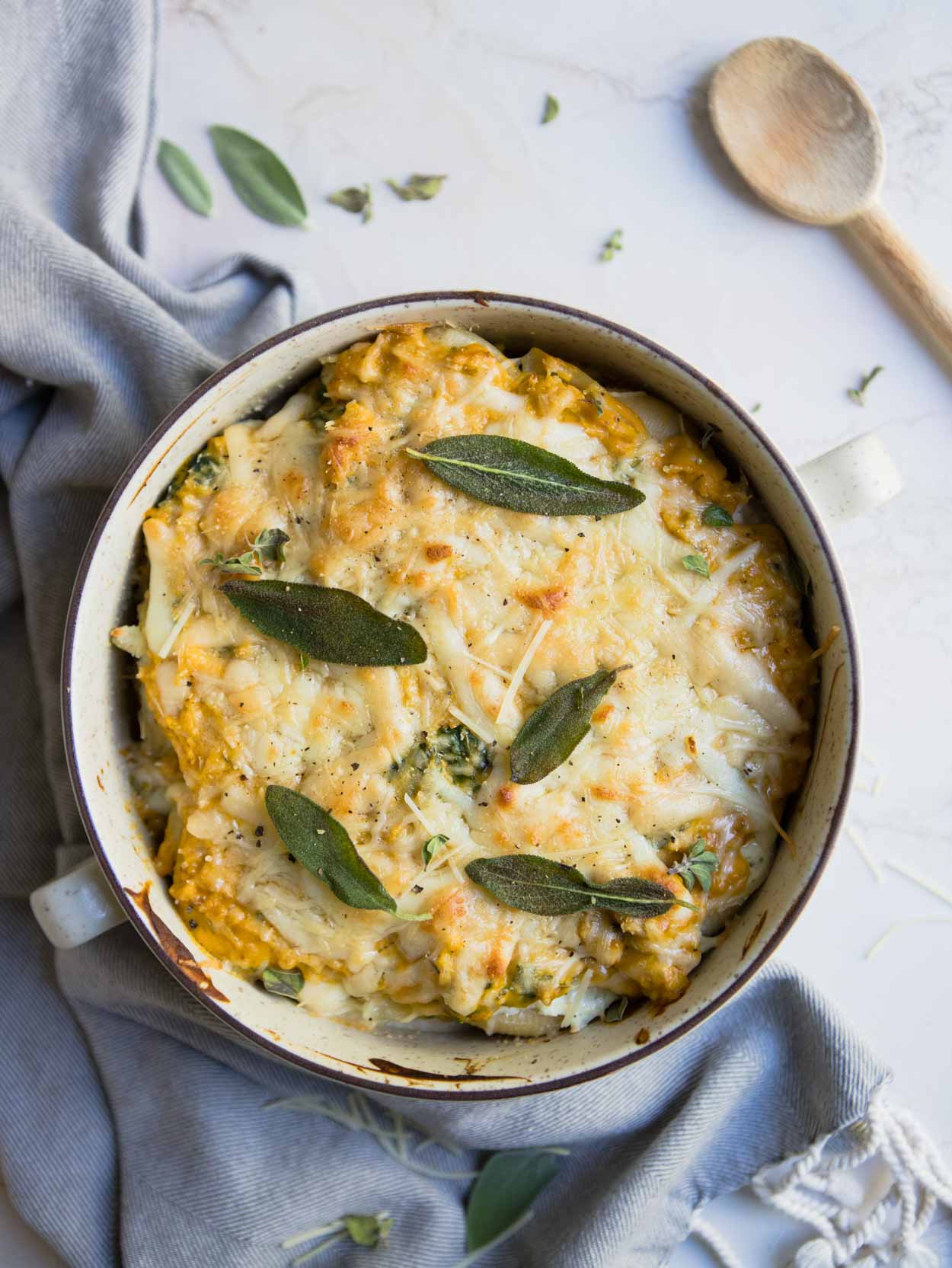 roasted butternut squash pasta sauce over stuffed pasta shells in a cream colored casserole dish on a white background