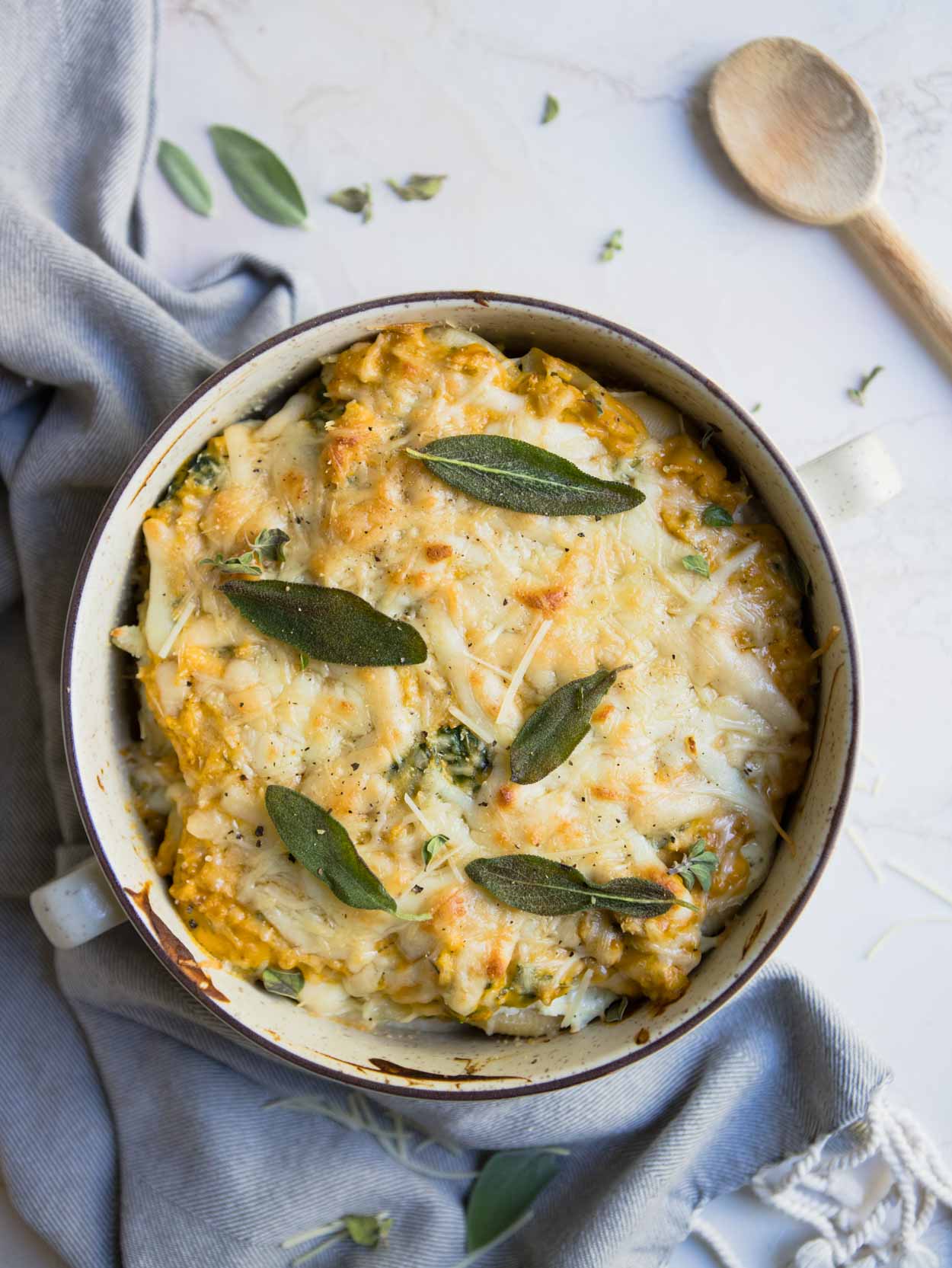 roasted butternut squash pasta sauce over stuffed pasta shells in a cream colored casserole dish on a white background 