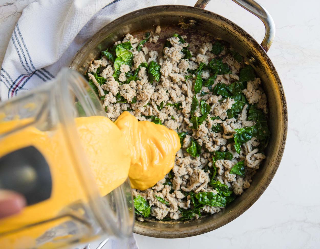 Ground turkey and kale with butternut squash being poured on top