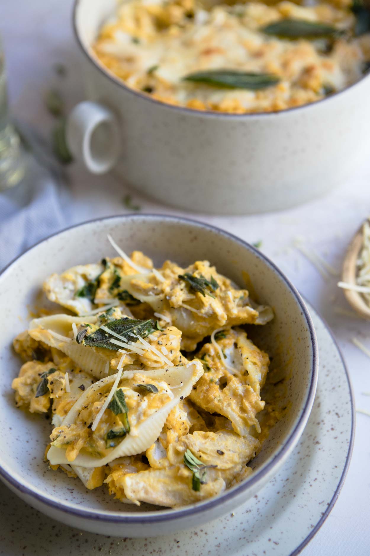 Stuffed pasta shells in a cream colored bowl on a white background