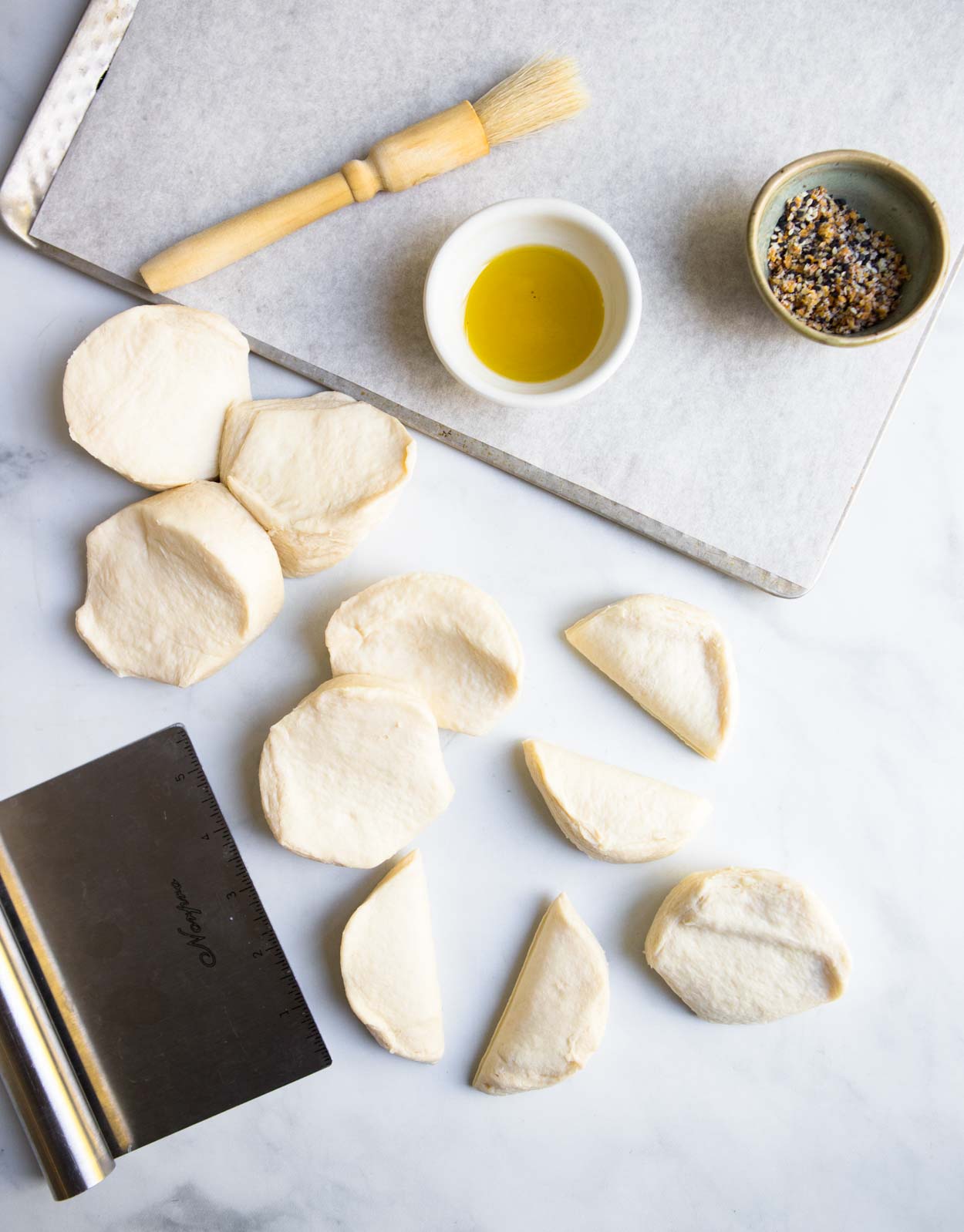 biscuit dough and olive oil and pastry cutter on marble surface