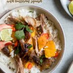 Woman's hand squeezing a lime over a bowl filled with rice and Asian pork shoulder