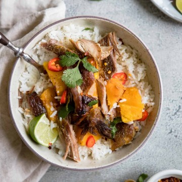 round bowl filled with rice, and topped with butternut squash, braised Asian pork shoulder and garnishes