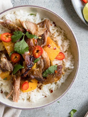 Round bowl filled with rice, Asian pork shoulder and garnishes