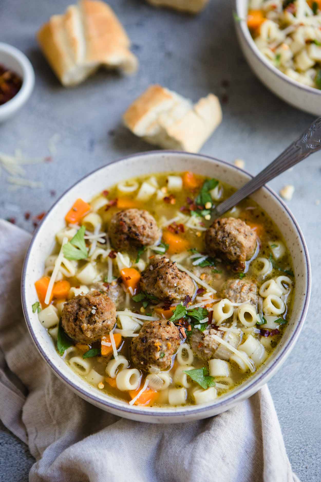close up of meatball and pasta soup with parsley and Parmesan cheese garnish