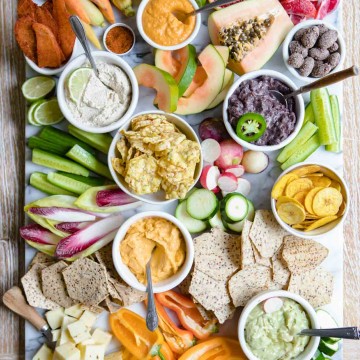 overhead shot of a fancy crudite platter with lots of fruits and veggies and snacks on a marble board