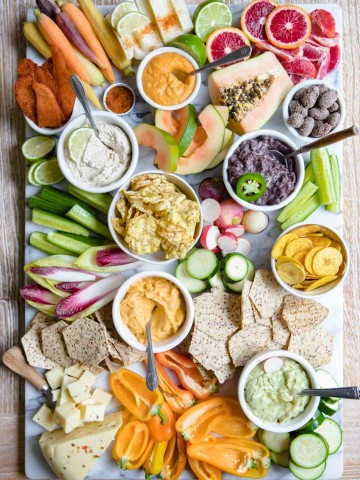 overhead shot of a fancy crudite platter with lots of fruits and veggies and snacks on a marble board