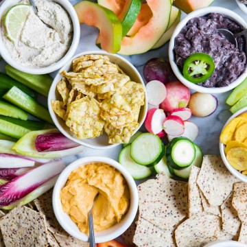 close up photo of fancy fruits and vegetables and crackers on a marble board for a crudite platter