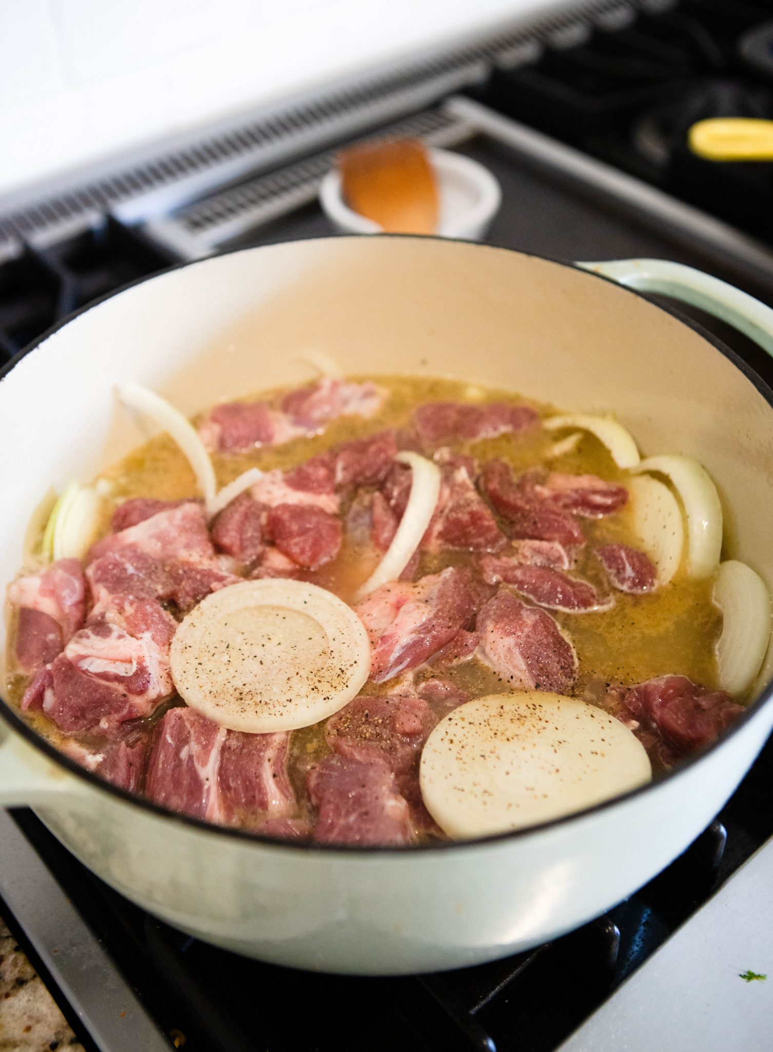 raw cubed pork butt with onions in a Dutch oven on the stove