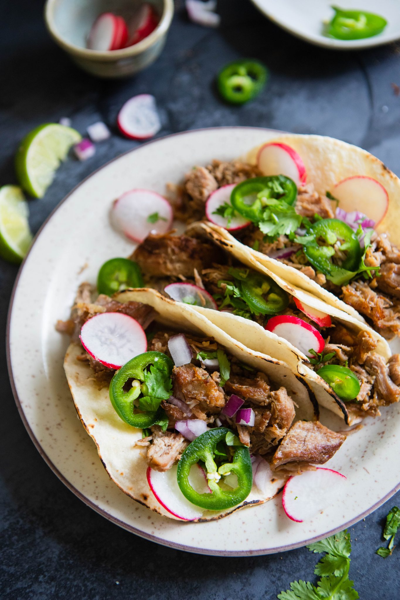 tacos stuffed with carnitas and topped with garnishes 