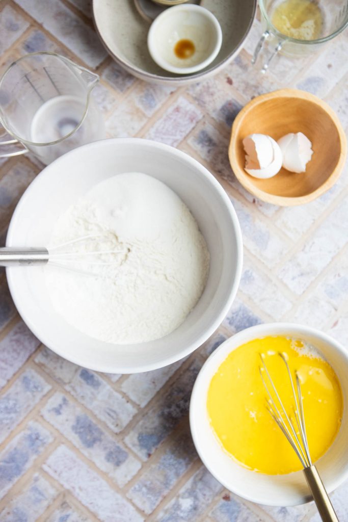 pancake ingredients in various bowls being prepared to cook pancakes. 