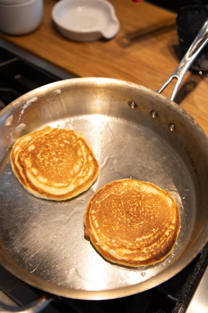 cooked pancakes on one side, cooking on the other side in a heated pan