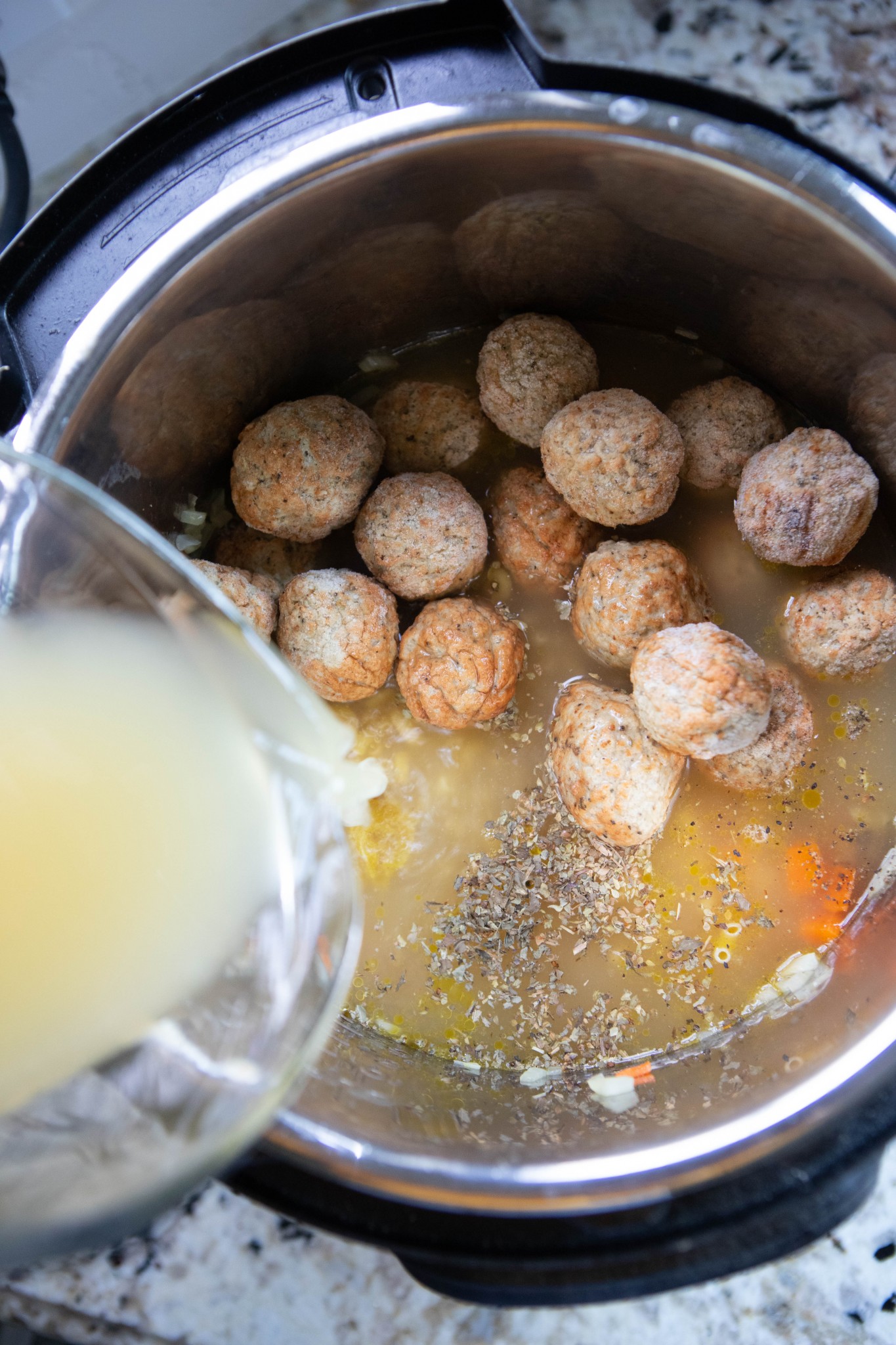 broth being poured over meatballs in an Instant Pot