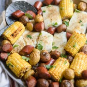 halibut, sausage, corn and potatoes on a round platter with seasoning on top