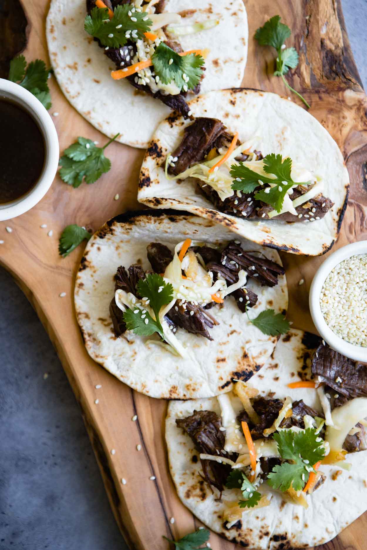 beef tacos with korean coleslaw topped on flour tortillas on a wooden board