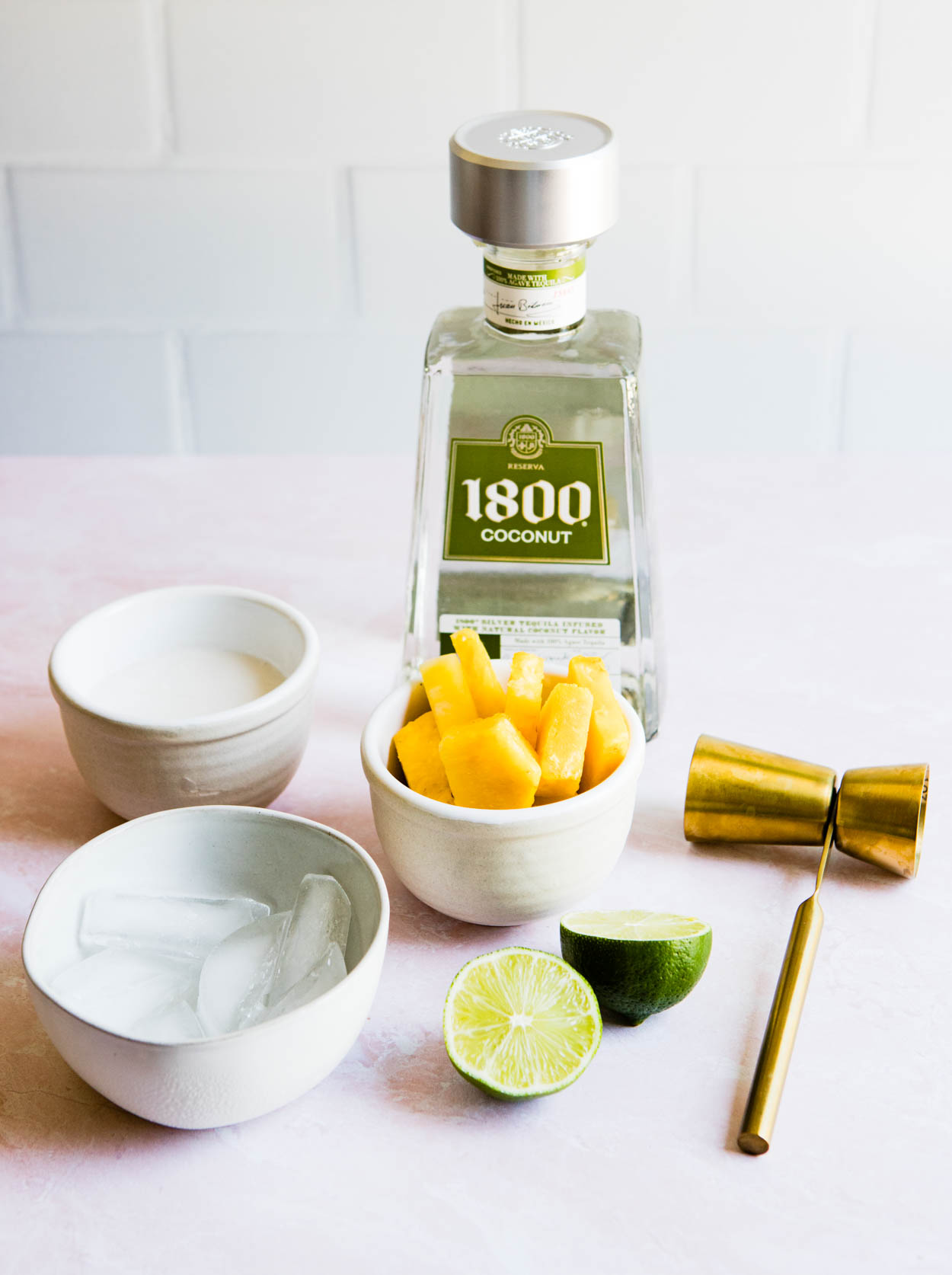 1800 coconut tequila with pineapple and ice and coconut milk in white bowls