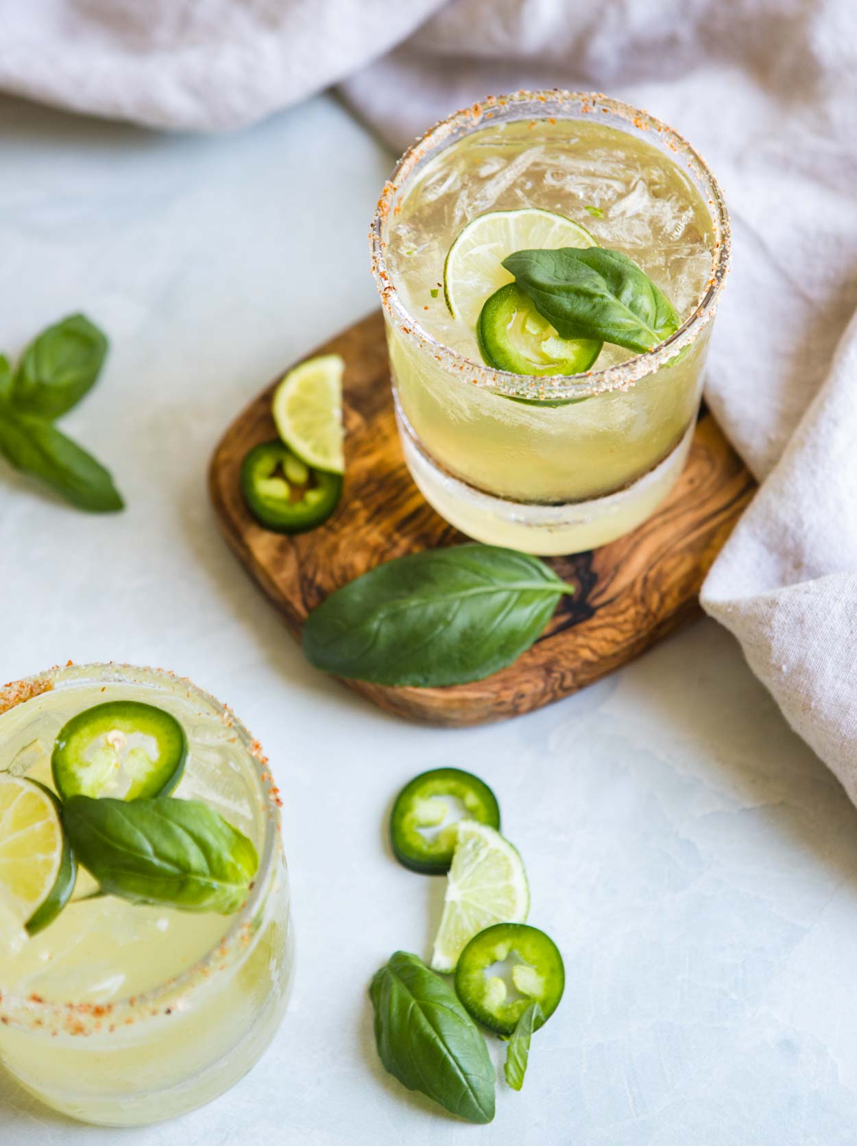 close up glass of jalapeno margarita recipe with lime, cucumber and basil garnish