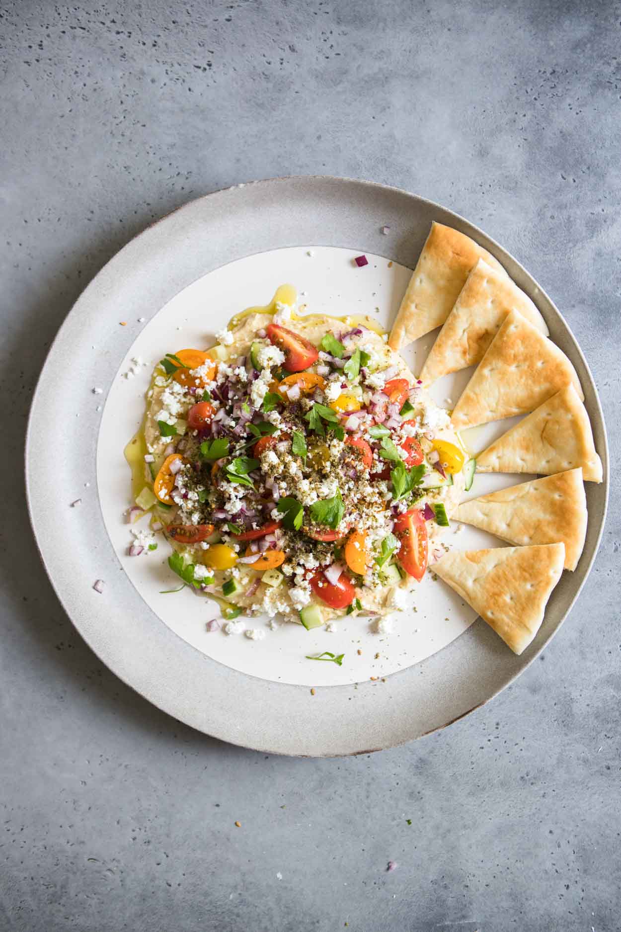 six pita wedges lined up around the hummus dip on the plate