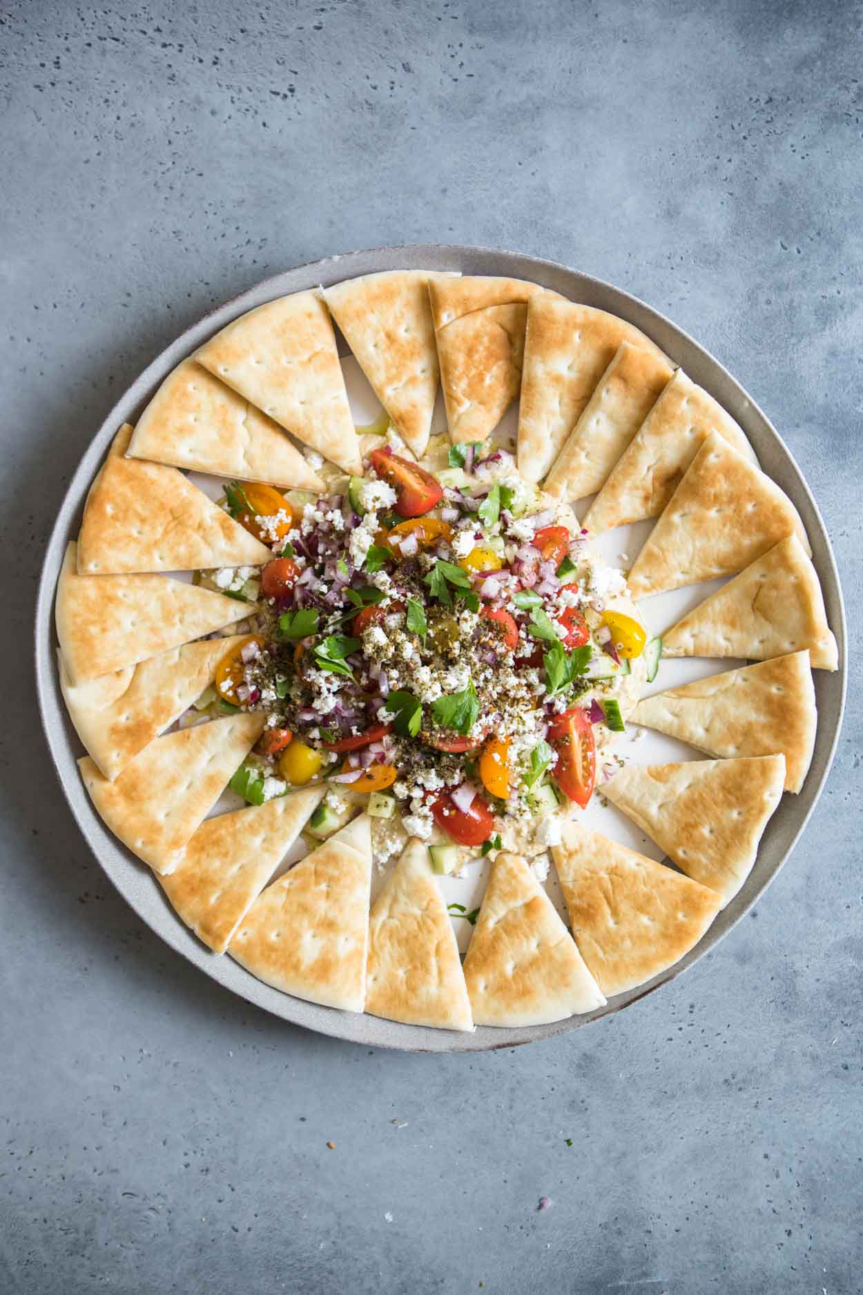 layered hummus dip surrounded by pita wedges