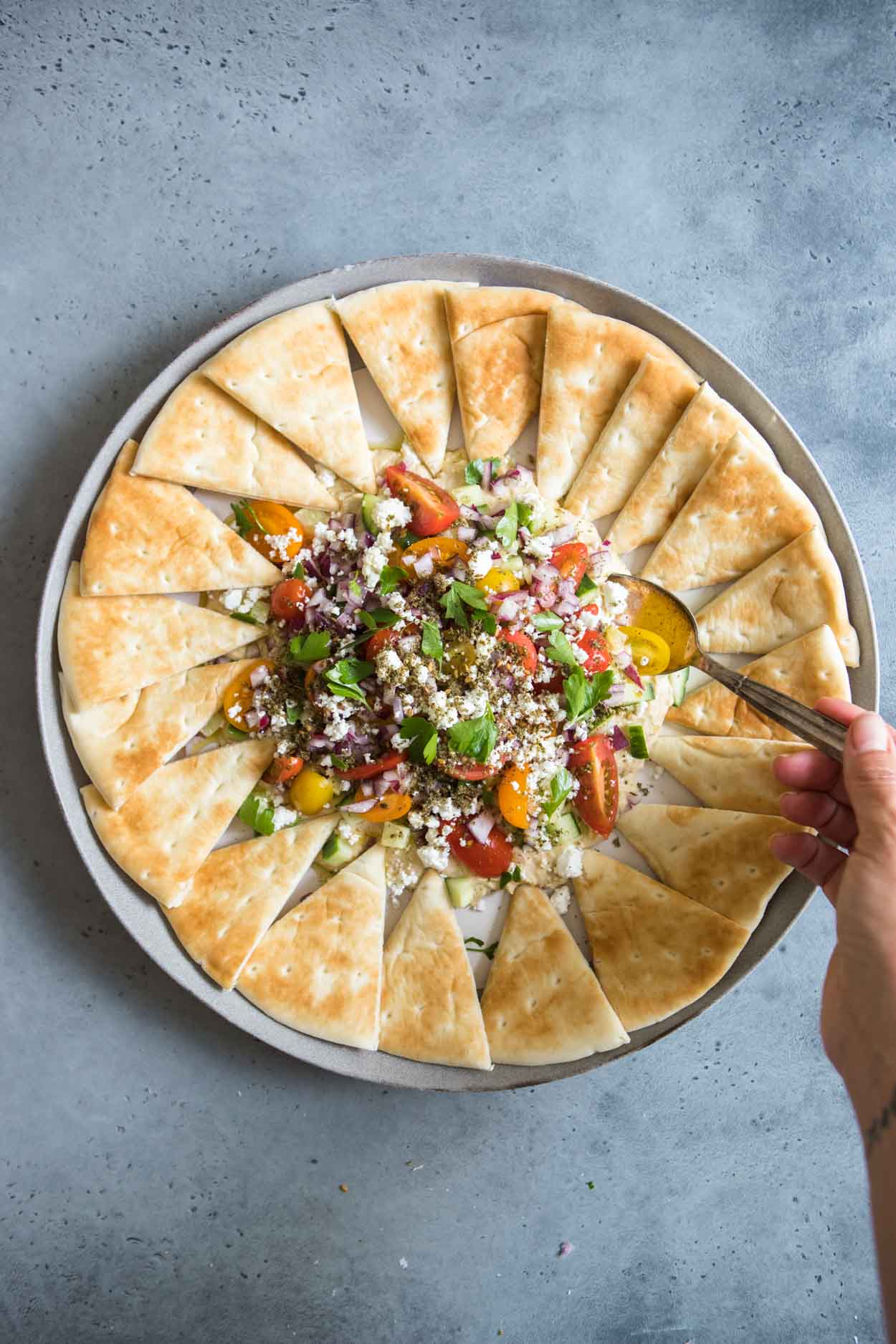 spoon digging into the layered hummus dip