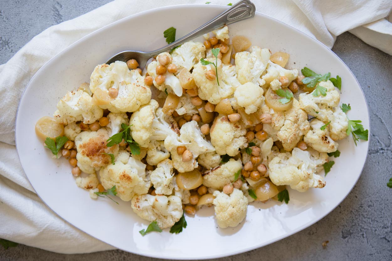 roasted cauliflower tahini dish in a platter with a serving spoon
