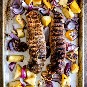 2 pieces of grilled pork tenderloin on a sheet pan, with grilled vegetables