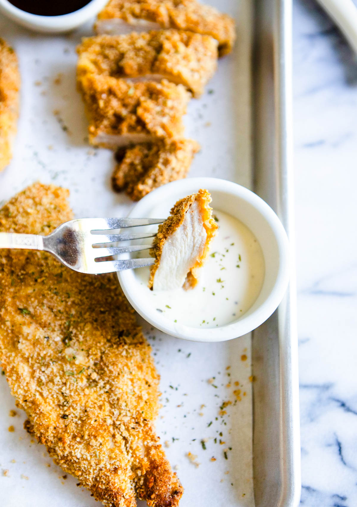 a piece of air fryer chicken breast being dipped in ranch dressing