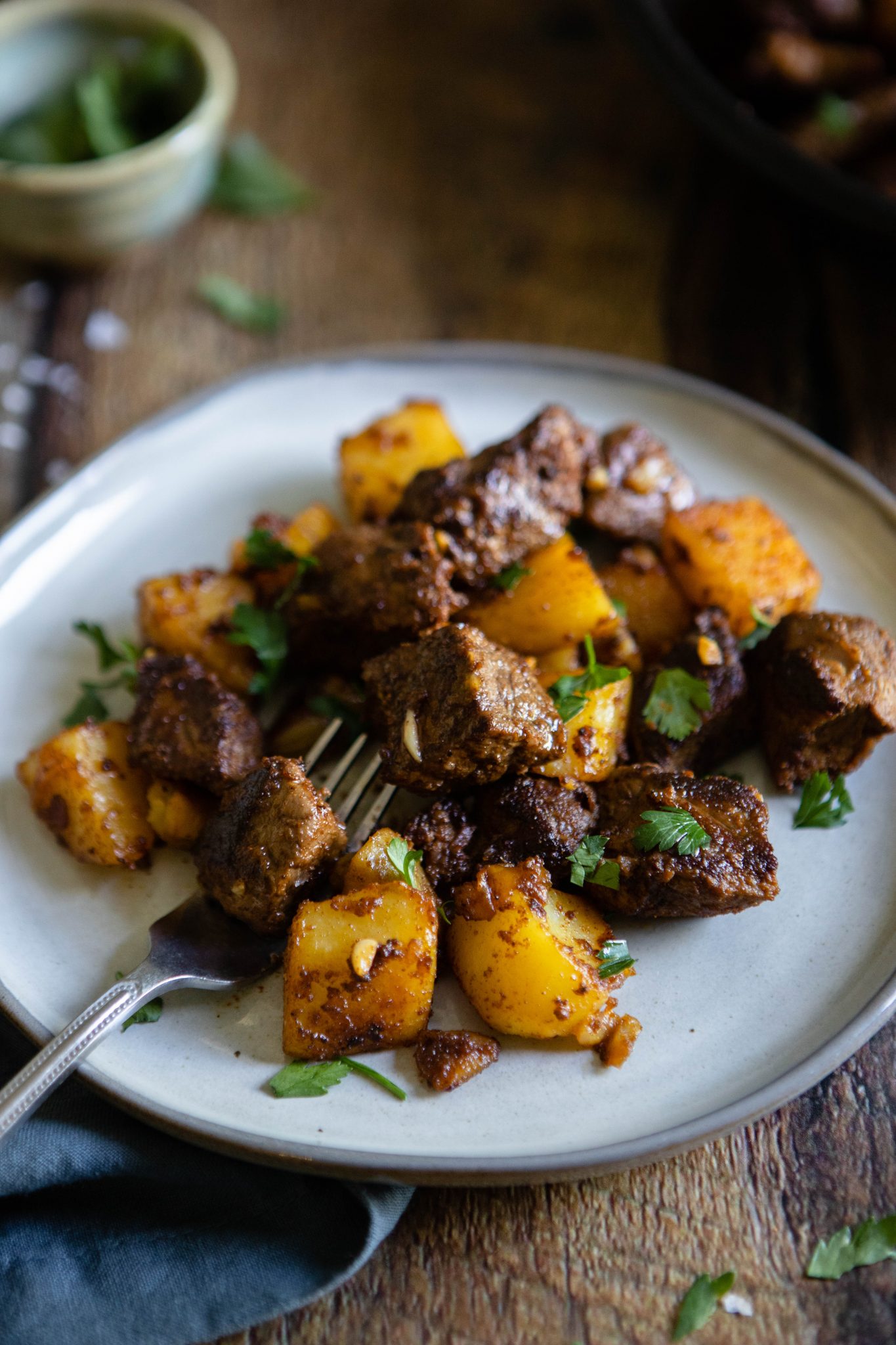 side angle of steak bites with cooked potatoes on a white plate
