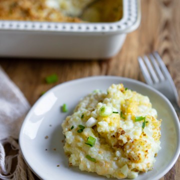 small white plate with cheese and potato casserole served on it, next to a silver fork