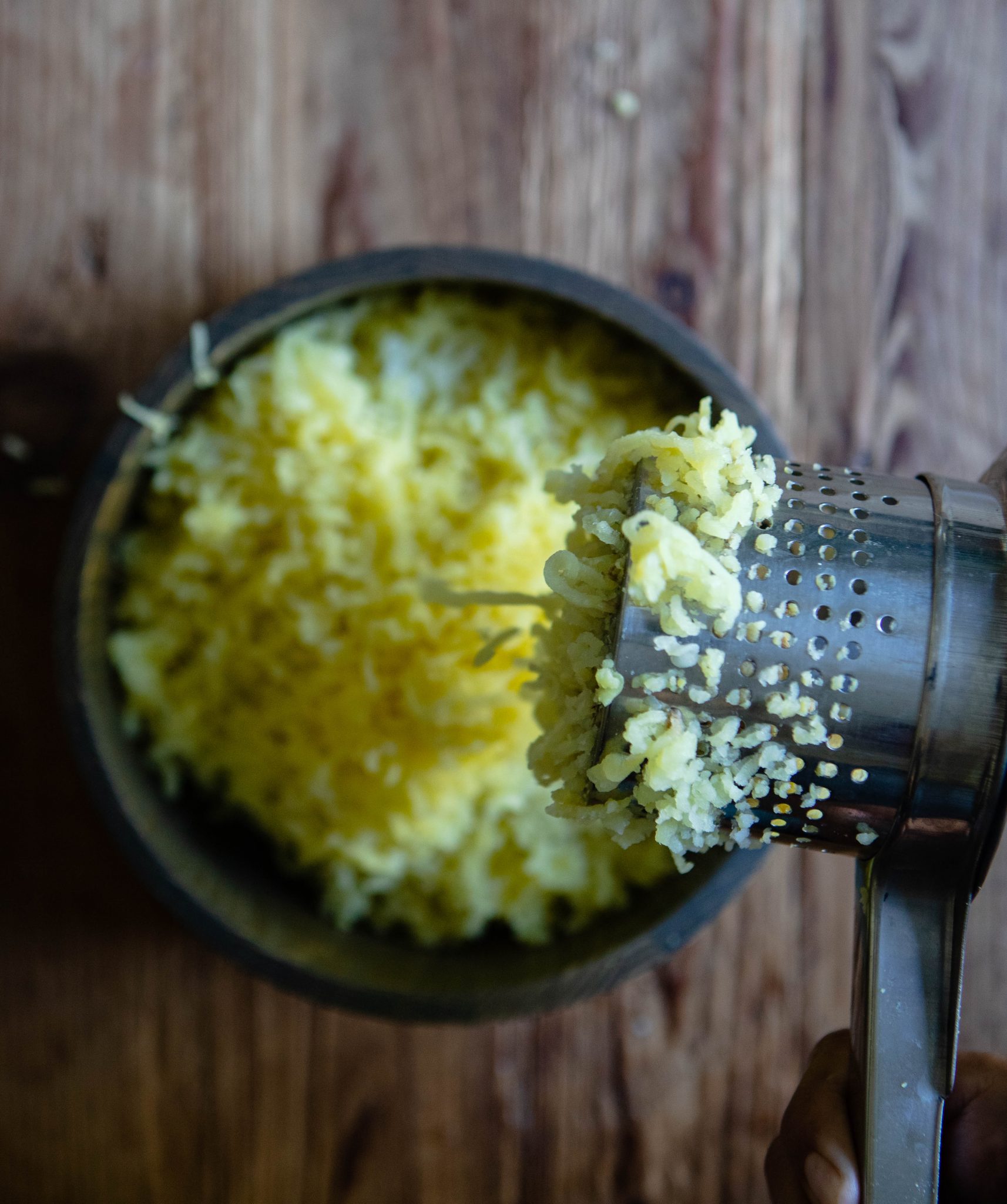 potato ricer ricing yellow potatoes into a bowl