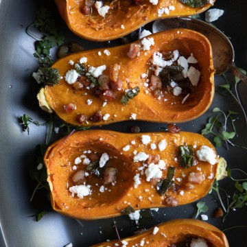 black platter with 4 roasted butternut squashes sprinkled with goat cheese and pancetta