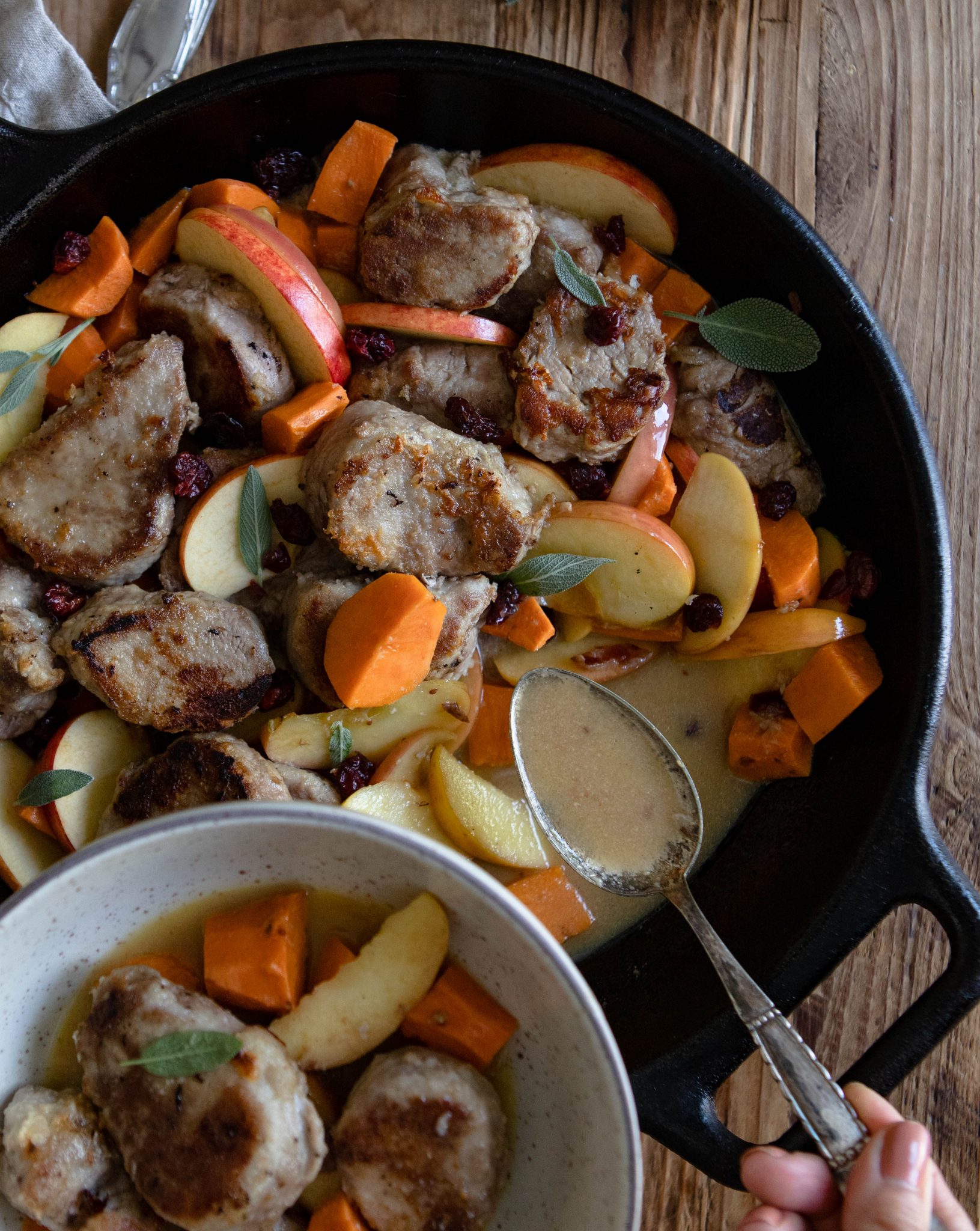 close up of pork tenderloin skillet dinner and scooping gravy into bowl