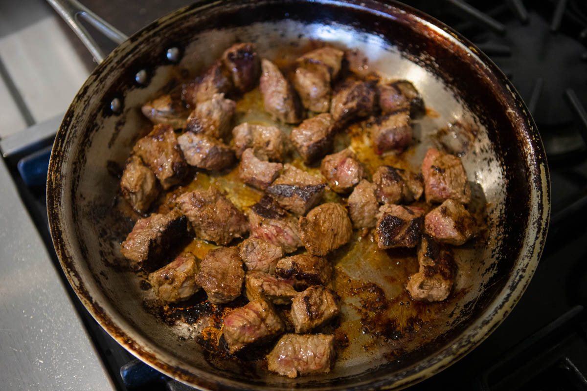 beef sirloin tip steak pieces sautéing in a skillet 