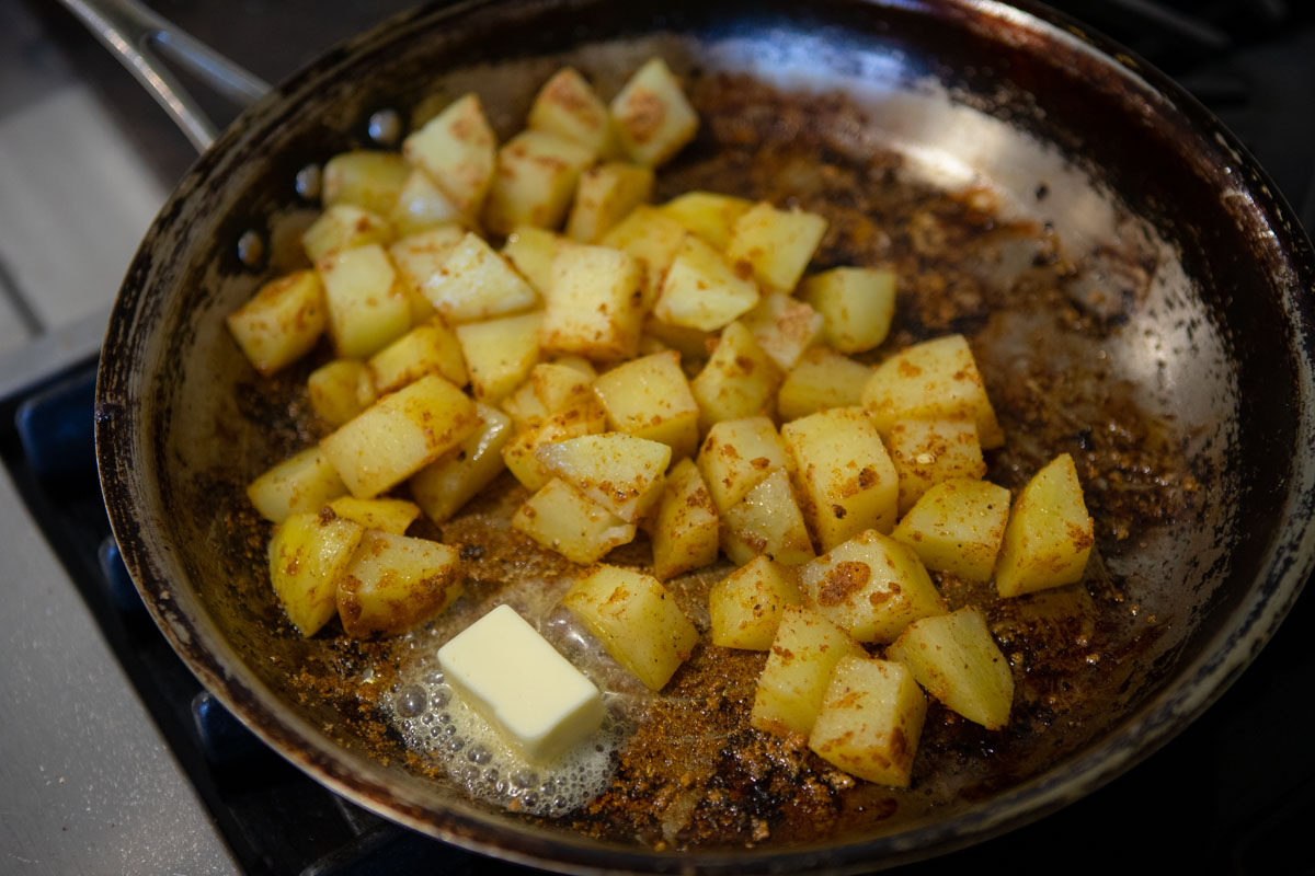 potato cubes cooking in a large skillet with butter 