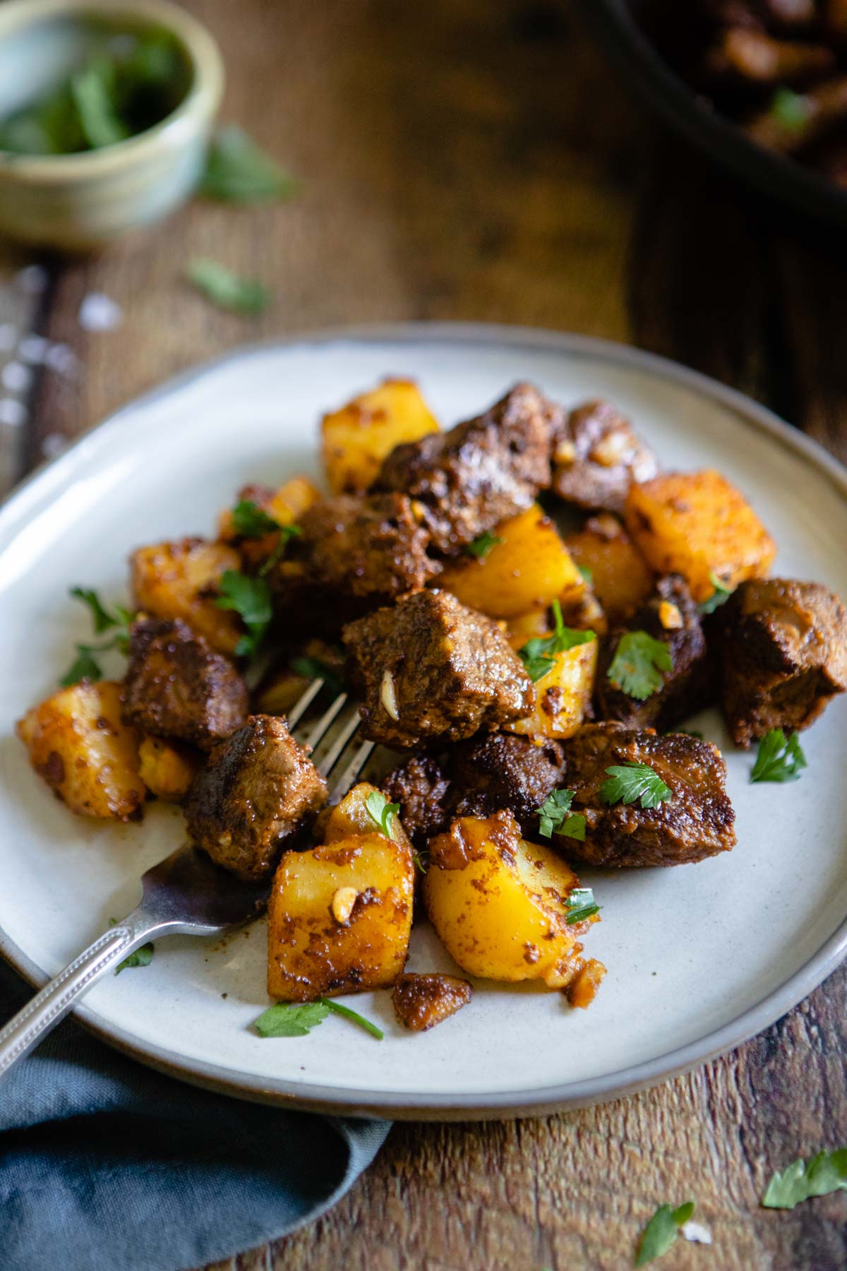 garlic and butter beef bites and potatoes on a gray plate with fork