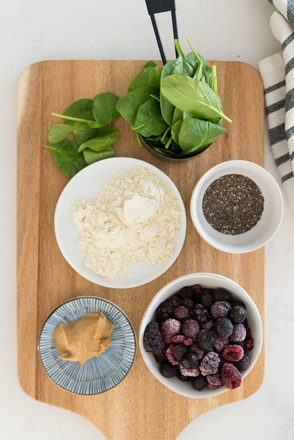 frozen berries, protein powder, spinach and chia seeds in round bowls