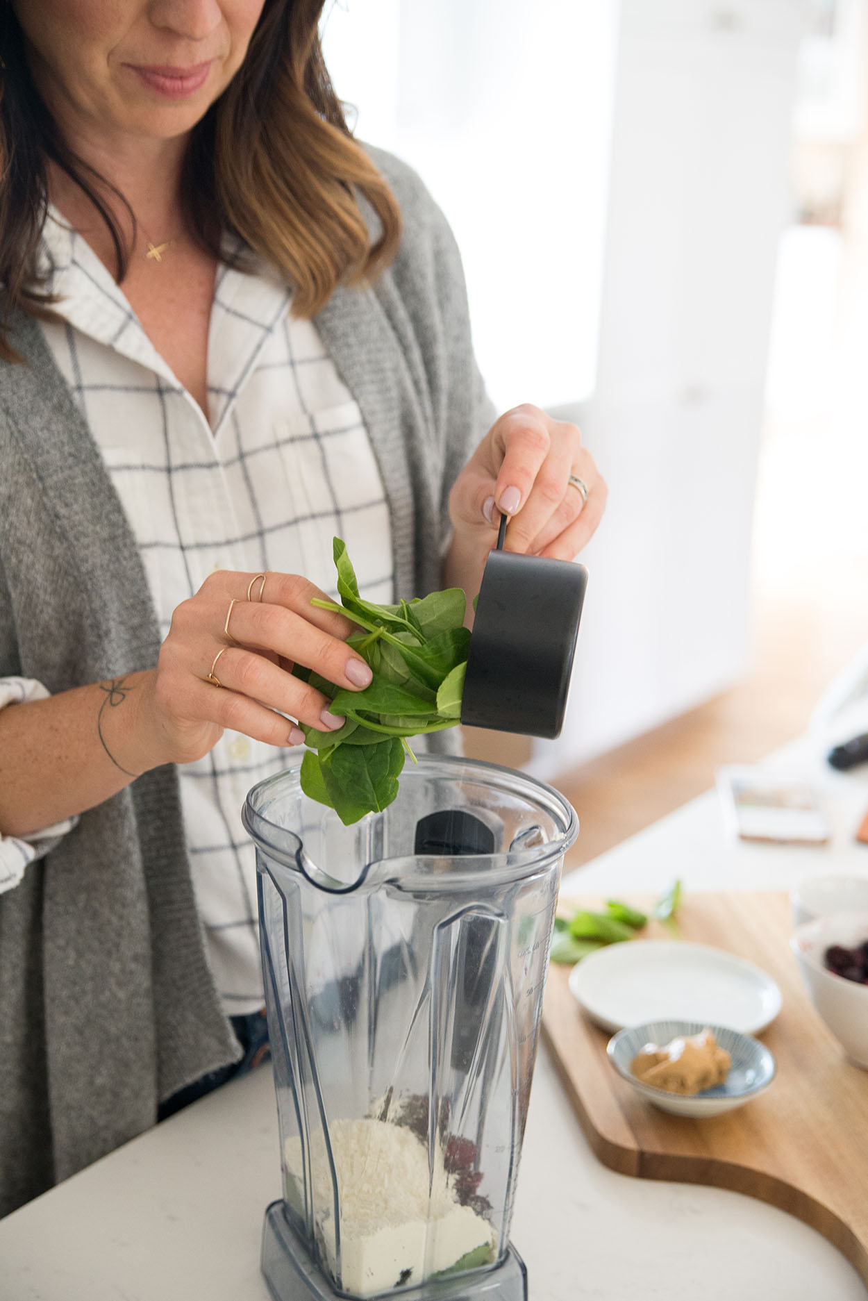 adding spinach to a blender to make a smoothie