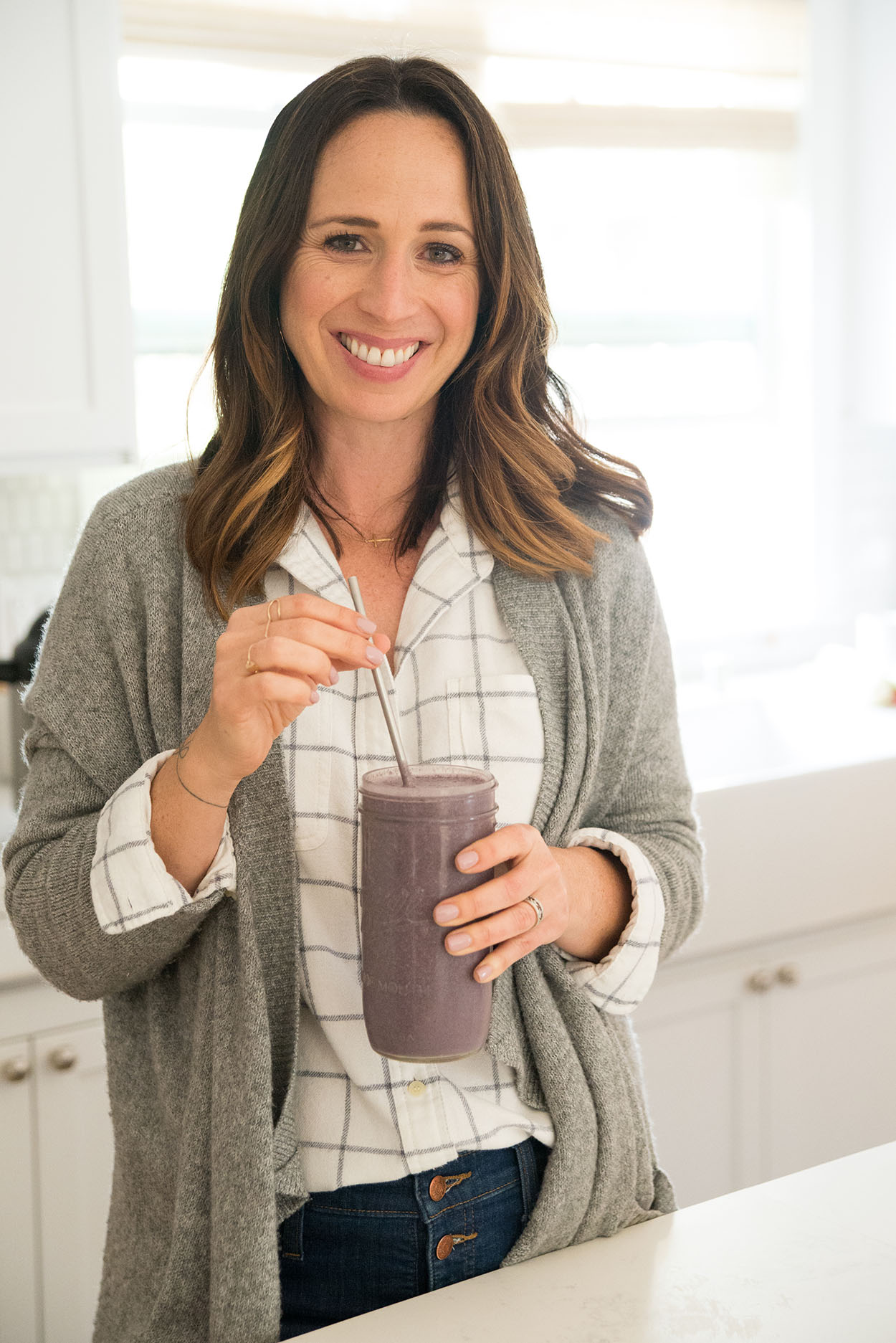 woman smiling holding a berry smoothie