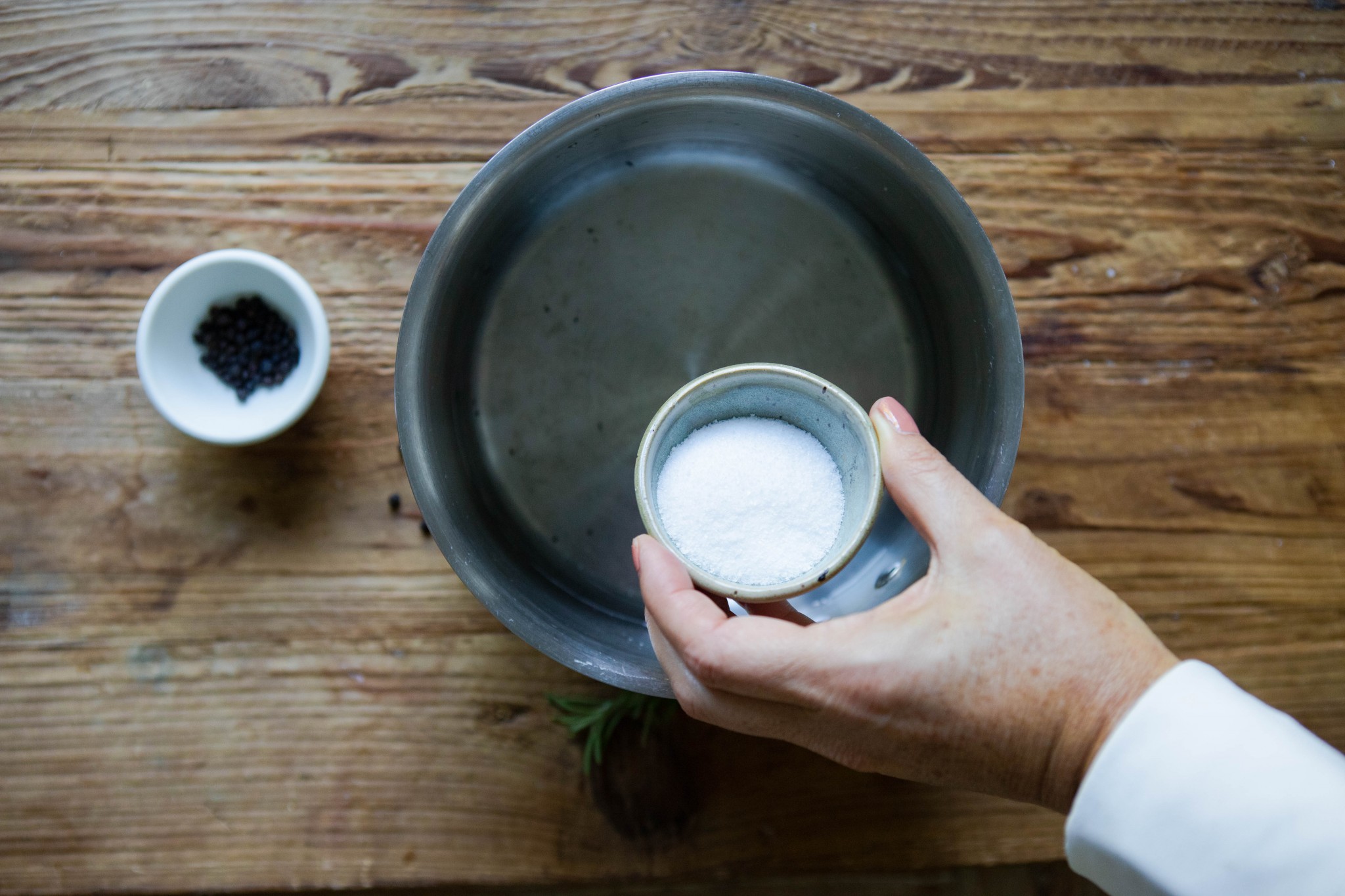 pouring Kosher salt into a saucepan filled with water