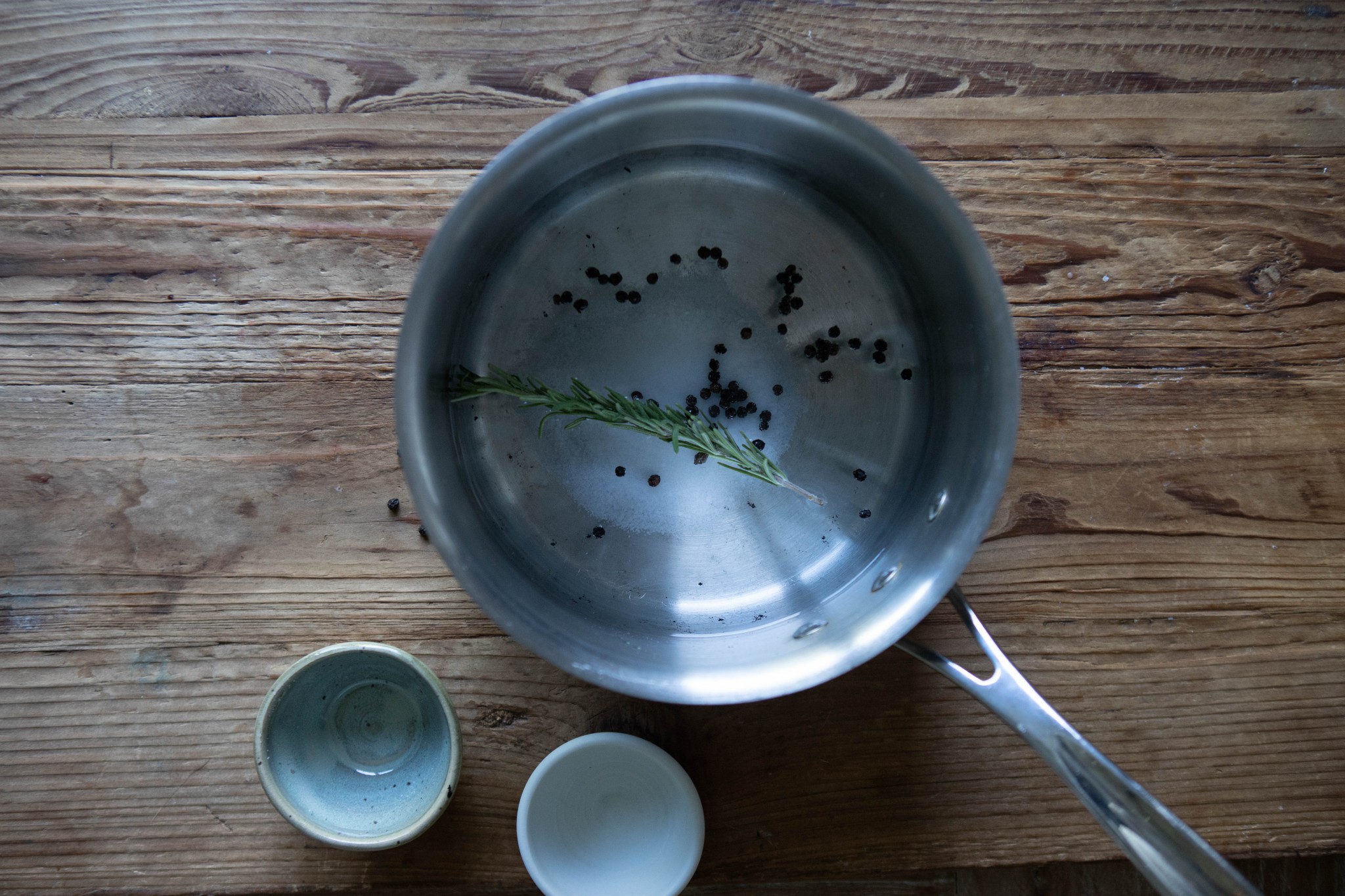 water and rosemary and peppercorns in a sauce pan