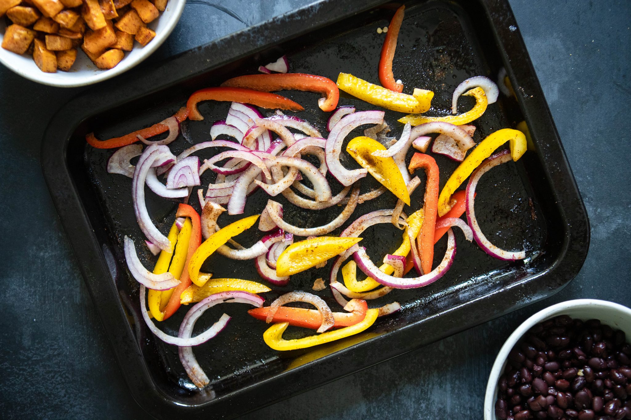 roasted peppers and onions on a black baking sheet