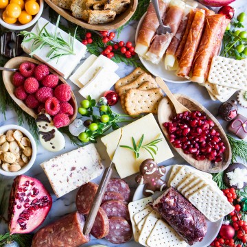 cured meat, blocks of cheese, fruit and nuts on a marble snack board