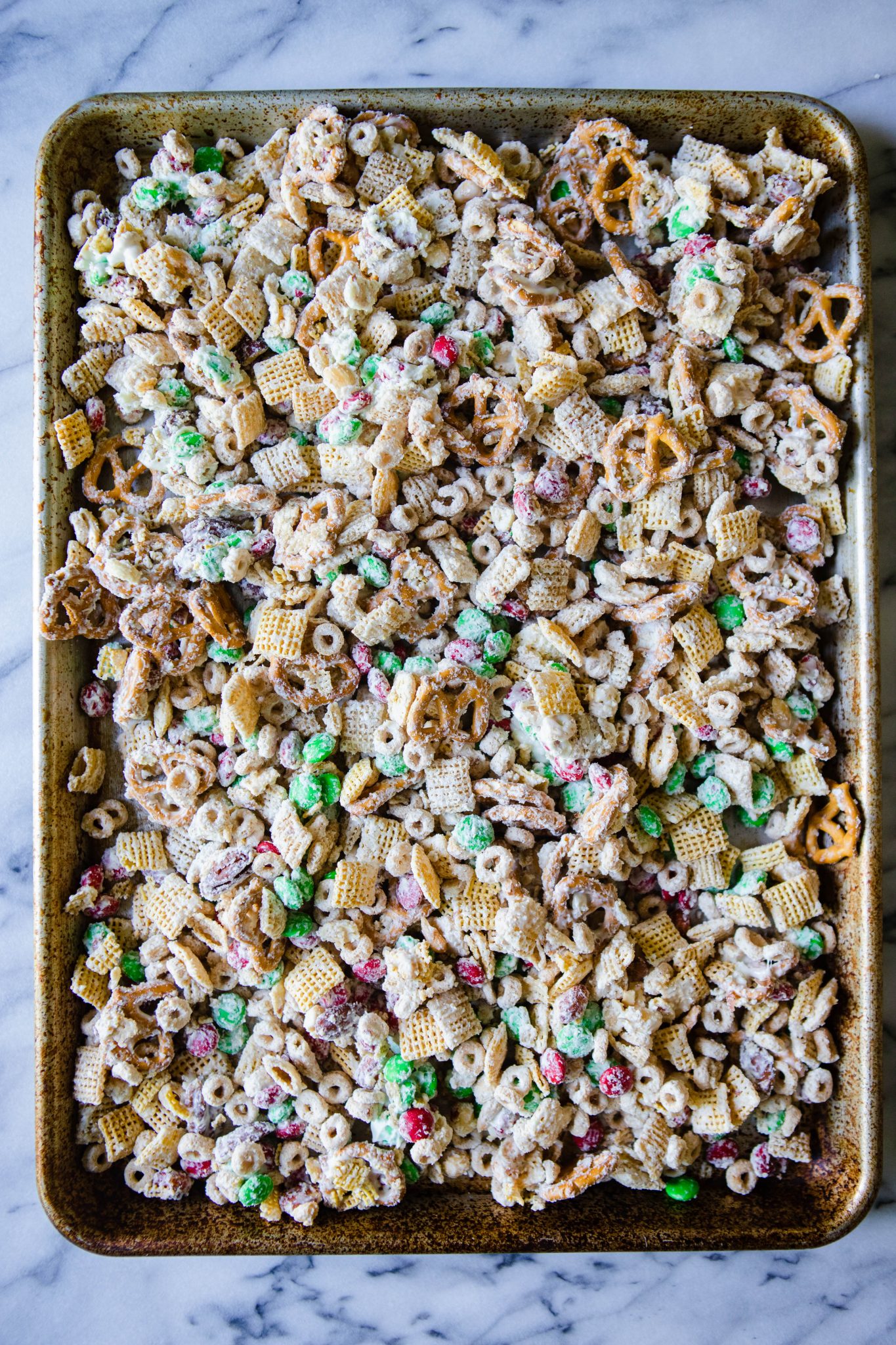 melted white chocolate chex mix spread out on a baking sheet