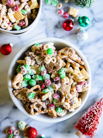 white chocolate, cheerios, rice chex, pretzels and mixed nuts mixed together in a white bowl