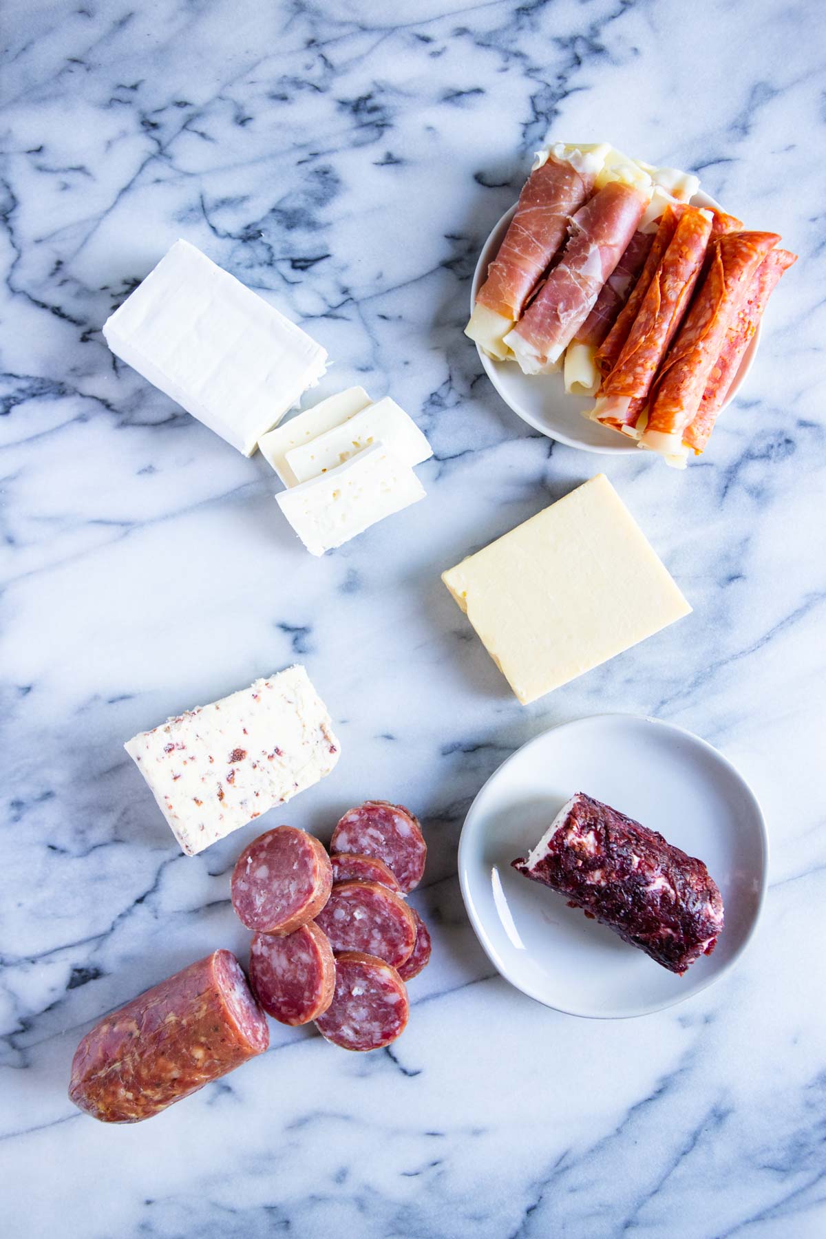cheese and cured meats spread out on a marble board